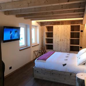 1 dormitorio con 1 cama y TV en la pared en Il Falco Affittacamere en Gallio