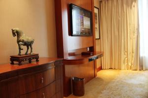 a room with a tv and a horse statue on a dresser at The Dragon Hotel Hangzhou in Hangzhou