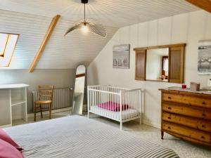 1 dormitorio con cuna, tocador y espejo en Gite, en Saint-Denoual