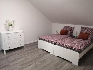 a white bedroom with a bed and a dresser at Ferienwohnung Nord/Süd in Nordenham