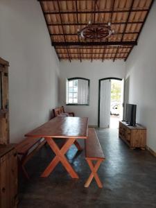 ein Esszimmer mit einem Holztisch und einem TV in der Unterkunft Casa Rio de Contas in Rio de Contas