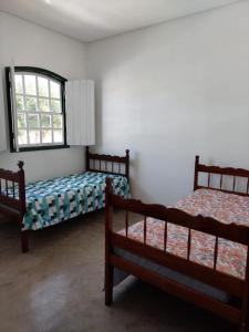 two beds in a room with a window at Casa Rio de Contas in Rio de Contas