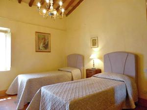 um quarto com 2 camas e um lustre em Agriturismo Fattoria Il Piano - Appartamento Antica Cucina - San Gimignano em San Gimignano