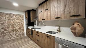 a kitchen with wooden cabinets and a stone wall at Arrels Terra - Apartamento boutique mediterráneo in L'Ampolla