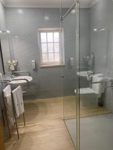 
a bathroom with a toilet, sink, and shower stall at Hotel Neptuno in Peniche
