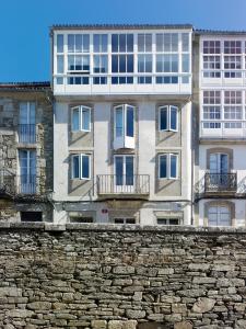 un edificio blanco alto detrás de una pared de piedra en Moure Hotel en Santiago de Compostela