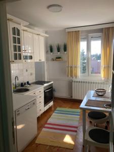 a kitchen with white cabinets and a sink and a table at Rustik Senjak in Sajmište