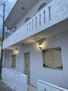 biały budynek z dwoma drzwiami i balkonem w obiekcie Philoxenia traditional house w mieście Palaiólimnos