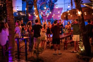 a group of people standing at a bar at night at Che Tulum Hostel & Bar Adults Only in Tulum