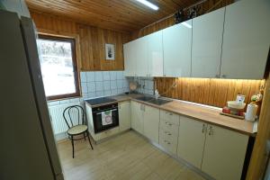 a kitchen with white cabinets and a chair and a stove at Casa de vacanta Satic Piatra Craiului La Doi viermi in Sătic
