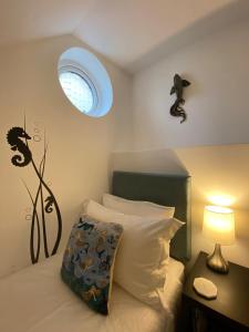 1 dormitorio con 1 cama con ventana y lámpara en Starboard Side Brixham - Ideal seaside getaway with parking en Brixham