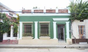 een groen en wit gebouw met gesloten ramen bij La Casa del Totumo in Santa Marta