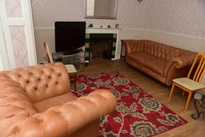 a living room with two leather couches and a television at CORBIERE GUEST HOUSE in Weston-super-Mare