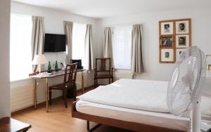 1 dormitorio con 1 cama, escritorio y ventanas en Hotel & Restaurant Sternen Köniz bei Bern, en Berna