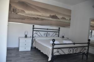 1 dormitorio con 1 cama y una pintura en la pared en Angelique Affittacamere en Santa Teresa Gallura