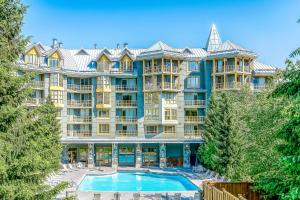 a large apartment building with a pool and trees at Cascade Lodge in Whistler