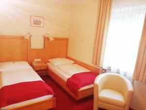 a hotel room with two beds and a chair at Pension Katrin in Salzburg