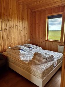 a bed in a wooden room with a window at Bright and Peaceful Cabin with Views & Hot Tub in Selfoss
