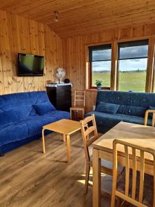 a living room with a blue couch and a tv at Bright and Peaceful Cabin with Views & Hot Tub in Selfoss