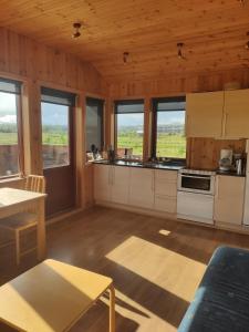 a kitchen with wooden walls and windows in a cabin at Bright and Peaceful Cabin with Views & Hot Tub in Selfoss