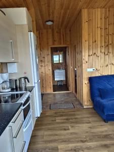 a kitchen with a blue couch in a room at Bright and Peaceful Cabin with Views & Hot Tub in Selfoss