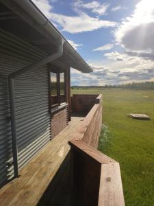 eine Holzterrasse an der Seite eines Hauses in der Unterkunft Bright and Peaceful Cabin with Views & Hot Tub in Selfoss