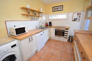 a small kitchen with a washer and a microwave at Maison Comps in Comps