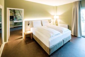 a bedroom with a large white bed and a window at Hotel am Zoo in Neunkirchen