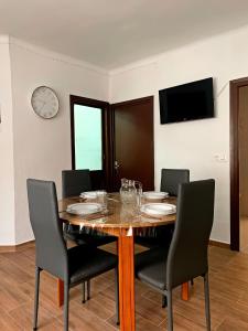 a dining room table with chairs and a clock on the wall at Una llar amb vista a L'Ampolla in L'Ampolla