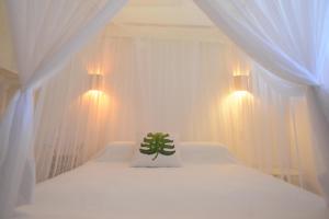 a bedroom with a white bed with a plant on it at Casa Alegre Trancoso, piscina, 3 suítes e ar-cond. in Trancoso +20 photos