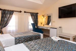 a hotel room with two beds and a television at Portakal Hotel Dalyan in Dalyan