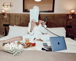 uma mulher deitada numa cama com um livro e um portátil em Hotel Green Town em Kutaisi