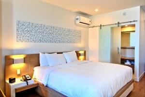 1 dormitorio con 1 cama blanca grande con sábanas blancas en Hôtel Le Navigateur, en Rimouski