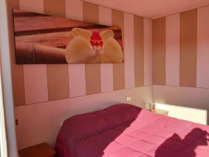 Un dormitorio con una cama rosa y una foto en la pared en La corte delle fate en Lonato