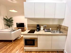 a kitchen with white cabinets and a couch in a living room at La plume dorée - Hotel de ville in Saint-Étienne +16 photos