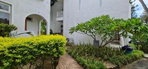 un edificio blanco con arbustos y un árbol delante de él en Ocean Villas Apart Hotel by Ocean Hospitality, en Grand Baie