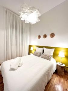 1 dormitorio con 1 cama blanca grande con almohadas blancas en La plume dorée - Hotel de ville en Saint Etienne