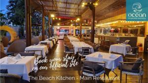 Un restaurante con mesas y sillas blancas y un bar. en Ocean Villas Apart Hotel by Ocean Hospitality, en Grand Baie