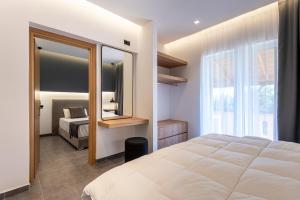 a bedroom with a large white bed and a mirror at Cirillo Family Hotel-Christinas Studios in Mastihari