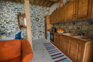 a kitchen with wooden cabinets and a stone wall at Anastasia's Home in Émbonas