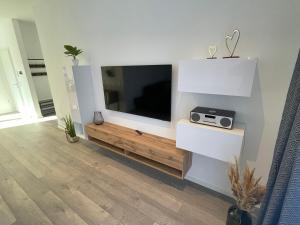 a living room with a flat screen tv on a wall at Lee-Moderne Neubauwohnung in Strandnähe - Wallbox in Wremen