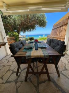 Une table et des chaises en bois sont disponibles sur la terrasse. dans l'établissement Just my dream beachfront Home 34 in Glyfada beach Corfu by New Era, à Glyfada