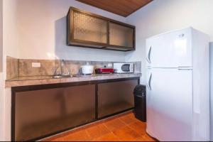 a kitchen with a white refrigerator and a counter at Hotel Cabinas el Tecal in Uvita