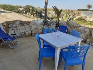 a white table and blue chairs on a patio at casa vacanza ginevra in Marzamemi