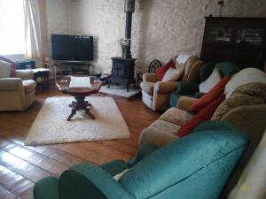 a living room with couches and a tv and a table at cwmddol fawr cottage in Carmarthen