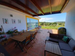 a patio with a wooden table and chairs and a couch at Casa dos Sobreiros in Cuba