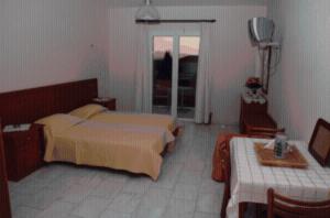 
a bedroom with a bed and a dresser at Barbara Studios & Apartments in Svoronata
