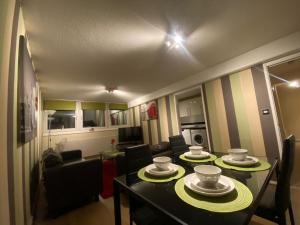 諾丁漢的住宿－Victoria Centre Apartments in the Victoria Centre Shopping Centre - Nottingham City Centre - 24 hours access - Most Central Location, Lounge, Full Kitchen, Washing Machine - Opposite Hilton by Restaurants & Shops - Outdoor Parking from five pounds a day，客厅配有带盘子的桌子