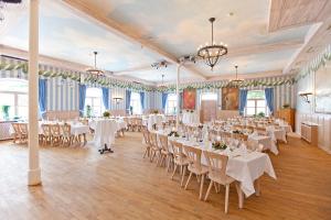 Un salón de banquetes con mesas y sillas blancas. en DIE POST Landgasthof Aufkirchen, en Berg am Starnberger See