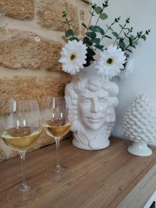 two glasses of white wine and a vase with flowers at Tesori di Girgenti in Agrigento